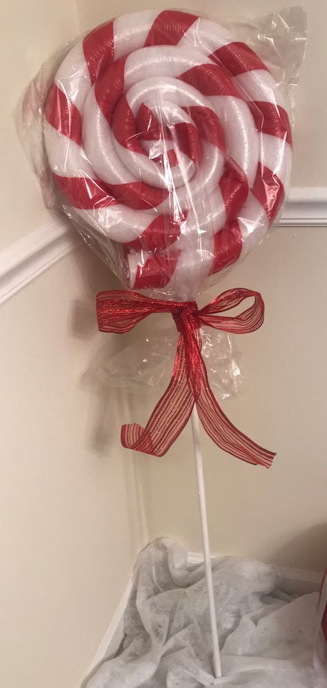 Giant lollipop made with pool noodles and duck tape. Wrapping is a gift basket bag from dollar store, and stick is wooden dowel from Walmart for  .97 spray painted white. White Pool Noodle Crafts, Pool Noodle Lollipops Christmas, Pool Noodle Candles, Birthday Decorations Diy, Pool Noodle Christmas Wreath, Yarn Ball Wreath, Giant Lollipop, Pool Noodle Wreath, Giant Lollipops