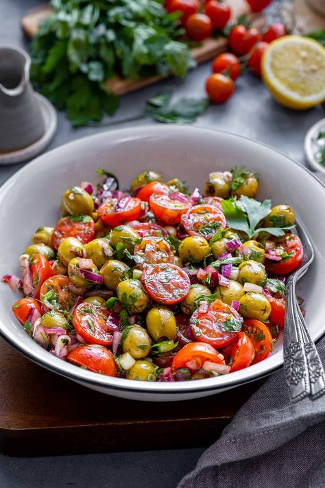 Discover the vibrant flavors of this refreshing Green Olive Salad, packed with fresh ingredients like tomatoes, onions, and herbs. This healthy and delicious salad is elevated by a tangy dressing made from lemon juice, sumac, and pomegranate molasses. Perfect as a side dish, light lunch, or potluck favorite, you'll love how the unique combination of ingredients creates a satisfying and unforgettable taste experience! Tomato And Olive Salad, Tomato Olive Salad, Green Olive Recipes, Green Olive Salad, Santa Cupcakes, Salad Recipes Lunch, Vegetables Salad, Unique Salad, Salad Lunch