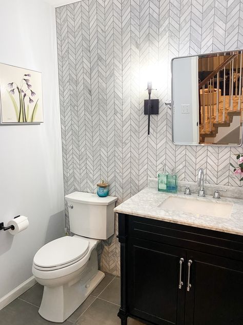 Another design project in the books! This powder room was transformed into a gorgeous modern oasis with a chevron tile backsplash/ accent wall, simple black vanity, marble counter top, and mixed metals of chrome and matte black finishes 🙌🏼.  #liketkit #LTKhome #LTKfamily @liketoknow.it @liketoknow.it.home http://liketk.it/2KQak Power Room Tile Wall, Tiled Walls In Powder Room, Powder Room Ideas With Tile Wall, Powder Bathroom Tile Wall, Tile Wall In Powder Room, Tiled Wall Powder Room, Powder Room Half Wall Tile, Powder Room Tile Accent Wall, Tile Behind Vanity Mirror