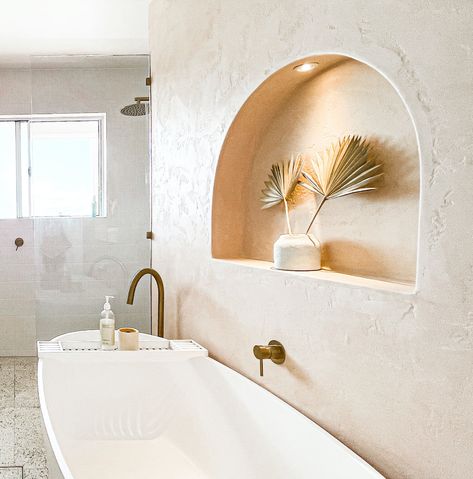 With an arched wall niche, peach Venetian render and timber vanity, this peach bathroom features a gorgeous tonal colour palette with stunning elements that make for a gorgeous coastal bathroom. In this bathroom tour, we have a close up of the arch wall niche in the peach feature wall with wall niche lighting, the white bath tub, brushed nickel tapware, terrazzo floors and the shower! Some would even describe this abthroom as earthy! To see more on this bathroom, click on the pin! Arched Wall Niche, Palm Springs Bathroom, Niche In Wall, Wall Niche Decor, Earthy Coastal, Wall Niches, Niche Decor, Niche Wall, Bathroom Niche