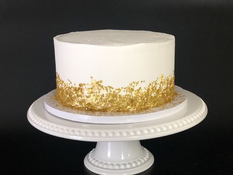 Watch this video to see how you too can make this elelgant white and gold cake! White Cake Gold Flakes, White Cake Gold Sprinkles, Gold Fleck Cake, Simple Wedding Cake White And Gold, White And Gold Birthday Cake For Men, Gold White Cake Birthday, White And Gold 40th Birthday Cake, White Cake With Gold Accents, White And Gold Smash Cake