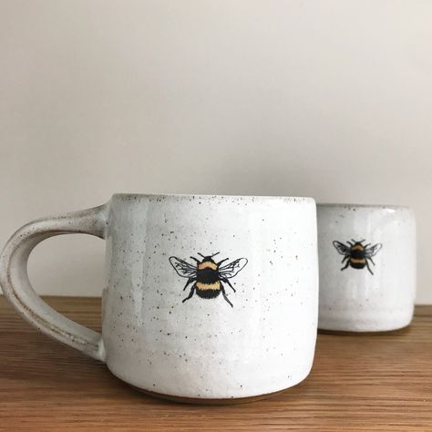 Bumble Bee mug by Heather Mathieson This gorgeous rustic ceramic bee mug has been wheel-thrown using a brown, stoneware clay - glazed with a food safe, glossy white glazeIt features a decal of one of Heather's bumble bee linocut images, which is an original designThe base is unglazed giving a lovely, rich contrast of textures and colours between the glaze and the raw clay bodyEach bee mug is handmade so please expect each one to be different in texture / detail +... Diy Keramik, Mug Diy, Bee Mug, Cerámica Ideas, Pottery Painting Designs, Rustic Ceramics, Keramik Design, Painted Mugs, White Mugs