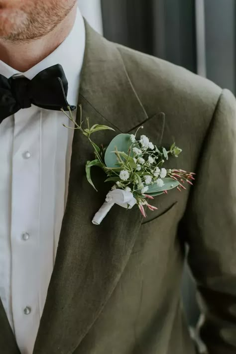 Groom in Green Suit Jacket Shows Boutonniere With White Flowers, Greenery Green And White Groom Suit, Enchanted Forest Wedding Suit, Dark Green Boutonniere Wedding, Green Notch Lapel Suit For Groom, Green Groom, Greens Boutonniere, Green Groom Suit, Ivory And Green Boutonniere, Elegant Green Wedding Lapel Pin