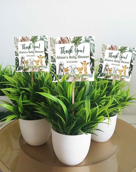 "Safari Faux plant baby shower favors MATCHING ITEMS! https://www.etsy.com/shop/HaleyMadisonDesign?ref=l2-shopheader-name&search_query=HM952 YOU GET - Faux leaves potted plant. Approximately 7\" tall by 2.5\" wide. This is a plastic plant on a plastic light weight pot base.  -Personalized tag size 2.5x2.5 glued to a wooden stick -Ready for you to decorate your guests will love decorating their homes with their beautiful party favor!  TO PURCHASE: 1.Choose the amount 2. Add to cart - leave personalization info (mom's name) 3. Complete your purchase You can always message me with any questions! I'm happy to help! This is for personal use only *OTHER DESIGNERS* Please don't copy my product designs. Legal action will be taken against Copyright Infringement. All product designs are licensed for Safari Shower Favors, Safari Baby Shower Table Decor, Safari Centerpieces Baby Shower Ideas, Safari Baby Shower Party Favors, Jungle Theme Baby Shower, Safari Baby Shower Boy Centerpieces, Jungle Baby Shower Centerpieces, Safari Baby Shower Centerpieces With Vases And Sand, Baby Shower Safari Theme Ellie's Party Supply