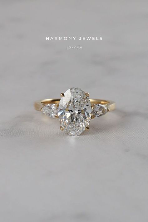 Side Stone Wedding Rings, Harmony Jewels London, Gold Oval Engagement Ring Side Stones, Oval Ring With Accent Stones, Oval With Trillion Side Stones, Oval Diamond Side Stones, Soft Gold Engagement Ring, Oval And Pear Trilogy Engagement Ring, Oval Ring Pear Side Stones