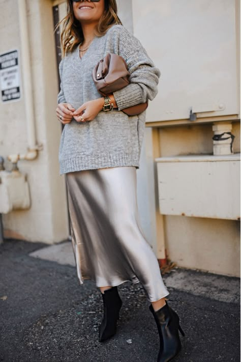 An easy way to elevate any winter outfit is with a silk midi skirt. Today Chic Talk is sharing how she styled this piece for a winter date night outfit! She pairs this silver silk skirt with some black heeled boots and a gray sweater for a comfy yet elevated date night look. Follow for more elevated outfit ideas, 2024 winter fashion, and date night outfit ideas. (I make commissions for purchases made through the link in this pin) Bias Skirt Outfit Winter, Silver Silk Skirt Outfit, Silk Midi Skirt Outfit, Metallic Skirt Outfit, Navidad Outfit, Midi Skirt Outfit Winter, Slip Skirt Outfit, Silk Skirt Outfit, Satin Skirt Outfit