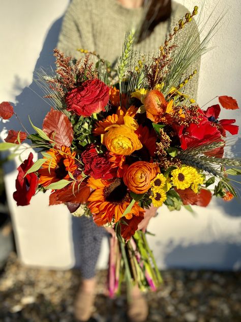 Dyed sunflower, red roses, red poppy, dahlias and fall leaves make the perfect free form fall bridal bouquet. Red Sunflower Bouquet, Dark Sunflower Bouquet, Wild Flower Fall Bouquet, Red Poppy Bouquet, Stardew Wedding, Dahlia Bouquet Fall, Red Sunflower Wedding, Gladiolus Bouquet, Dark Red Wedding