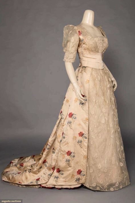 Up for auction March 28, 2020 - Historic Fashion Online Bellows Falls Trained evening gown of blond silk satin w/ warp-printed red, yellow & blue flowers over embroidered net, w/ satin cummerbund sash closure, originally 1880s, altered c. 1900, B 33", W 23", L 58-77", (underarms worn, few tiny holes/ wear to back of skirt , train dirty, wear to net at CF closure) good. MCNY Victorian Evening Gown, 1880s Dress, 1900s Costume, Yellow Blue Flowers, Historical Gowns, 1890s Fashion, Silk Evening Gown, Historic Fashion, Era Fashion