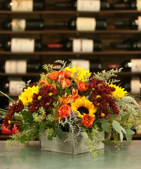 This gorgeous, sprawling centerpiece gives “bountiful” a whole new meaning. A simple low box filled with carnations, fall leaves, and Red Rover Chrysanthemum,  Orange roses, sunflowers, fall’s loveliest accent flowers and greenery, with vicking daisies.  thanksgiving, centerpiece, red rover, vicking daisy Thanksgiving Floral Centerpieces, Thanksgiving Flower Centerpieces, Thanksgiving Decorations Diy Table, Thanksgiving Floral Arrangements, Fall Floral Centerpieces, Red Centerpieces, Accent Flowers, Thanksgiving Floral, Thanksgiving Flowers