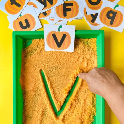 A finger writes the letter "v" in orange salt in a green shallow tray. Sitting in the tray is the letter "v" on a pumpkin cut from paper, and on the table above the tray are other pumpkin letters cut from paper. Pumpkin Activities Preschool Free Printable, Pumpkin Activities Preschool, Sensory Writing, Writing Center Preschool, Orange Salt, Letter Centers, Pumpkins Preschool, Preschool Journals, Fall Sensory