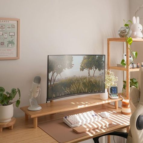 Minimalist desk setup in a bright room, featuring a wide monitor displaying a nature scene, surrounded by small plants and plush toys. The workspace includes a light wooden desk with a white ergonomic chair, and decorative items such as a gaming poster and a small white bunny figurine. Minimal Home Office, Cozy Minimalism, Positive Environment, Dream Desk, Desk Setups, Cozy Home Office, Minimalist Desk, Desk Goals, Office Room Decor