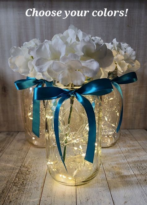 "Your choice of pint size or quart size mason jar includes one set of warm white LED fairy lights, and one silk hydrangea (choose color from available options), and a ribbon bow (choose color). These centerpieces are very popular for weddings, baby showers, parties, corporate events, holiday events, and any other event that requires table centerpieces. They also look great in any room of your house or office. To see other lighted jar options and all of my other listings, please view my shop: htt Mason Jars With Lights, Led Centerpieces, Blue Table Settings, Mason Jar Centerpiece, Blue Centerpieces, Lighted Centerpieces, Silver Centerpiece, Lights Wedding Decor, White Centerpiece