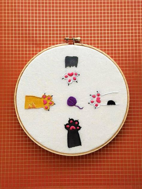 This handcrafted embroidery piece is not just an artwork but a celebration of the diverse personalities and colors that cats bring into our lives. Cats are naturally drawn to lines, and this design beautifully captures their affinity for the elegant curves and shapes. Cat Paw Embroidery, Embroidered Cat, Cat Embroidery, Colorful Cat, Cat Colors, Cat Paws, Orange Cat, Embroidery Hoop, Embroidery Art