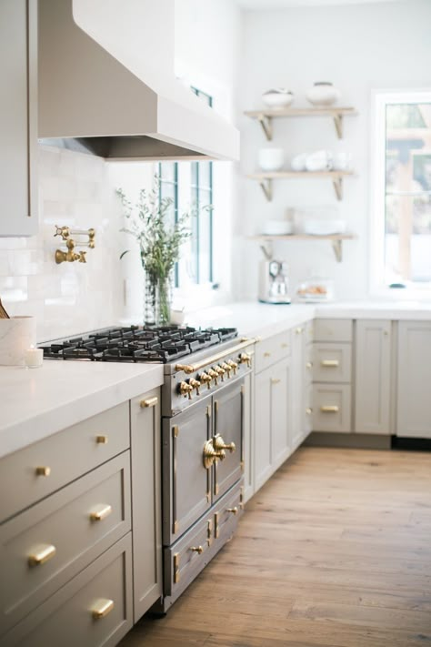 Light green kitchen cabinets with brass handles and a European stove with white marble countertops. Light Grey Kitchen Cabinets, Light Grey Kitchens, Light Gray Cabinets, Light Wood Floors, Bright Kitchens, Home Luxury, 아파트 인테리어, Remodel Kitchen, Grey Kitchen Cabinets