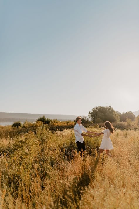 Couple sitting on the ground kissing and cuddling with each  other during their engagement session. Fall Golden Hour Couples Shoot, Fall Sunset Engagement Pictures, Outside Couples Photoshoot, Landscape Engagement Photos, Golden Hour Engagement Shoot, Running Engagement Photos, Engagement Photos Golden Hour, Fall Engagement Photos Ideas, Golden Hour Couples Shoot