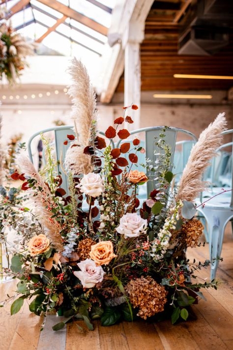 Chicago florist, Romee Willow Florals, created these floral hedges for a fall wedding ceremony at The Joinery. Elements include toffee roses, pampas grass, white dahlias, eucalyptus, and other dried elements in these artistic floral arrangements. We repurposed these floral hedges and placed them in front of the sweetheart table during the reception. To see more photos of their textured, autumnal floral decor by Allison Williams Photography, visit our blog through the link. Pampas Grass And White Rose Bouquet, Fall Wedding Aisle Flowers, Eucalyptus Fall Wedding, Dried Flower Table Arrangements, Fall Wedding Ceremony Flowers, Autumn Flowers Wedding, Floral Hedge, Pampas Arrangement, Fall Wedding Ceremony Decorations