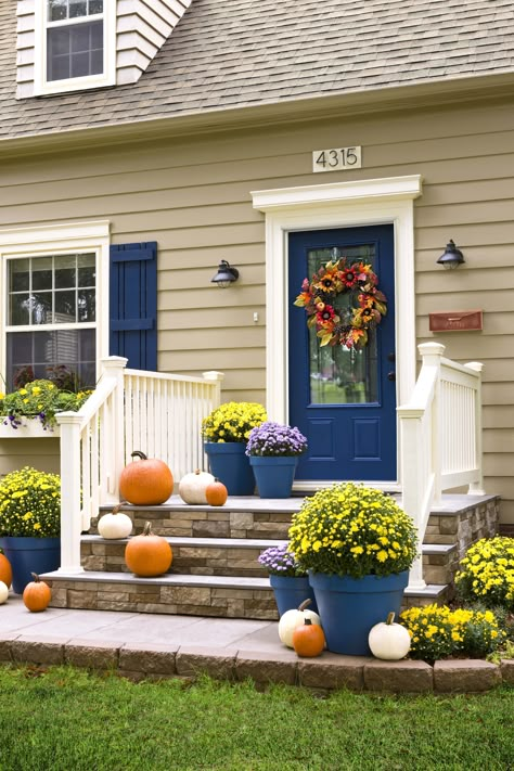 Add to the curb appeal of your house -- and increase its value -- with these easy exterior improvements. Welcome autumn in all its glory with a fall-themed door wreath. This ready-made decoration brings together a colorful mix of faux flowers, leaves, and other signs of the season. Best of all, it’s reusable year after year. Transform a slab and steps with the high-end look of stone. Then update a basic mailbox with gleaming copper spray paint. Tan House, Blue Shutters, Casa Country, Door Colors, Pintura Exterior, Front Steps, Front Door Colors, Casa Exterior, Exterior Stone