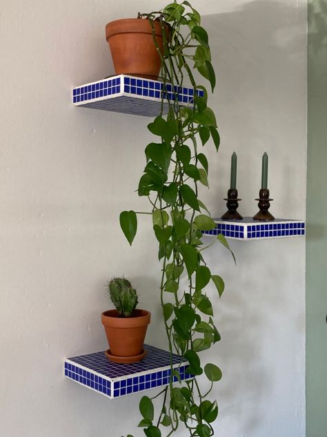 Floating shelf. Cobalt blue tiles, flowing plant, cactus, brown candleholders, green candels. Cobalt blue tiles Diy Tile Shelf, Tile Nightstand Diy, Green Tile Nightstand, Disco Tile Shelf, Tile Corner Shelf, Diy Tile Side Table, Tile Plant Stand, Funky Shelf, Tiled Shelf