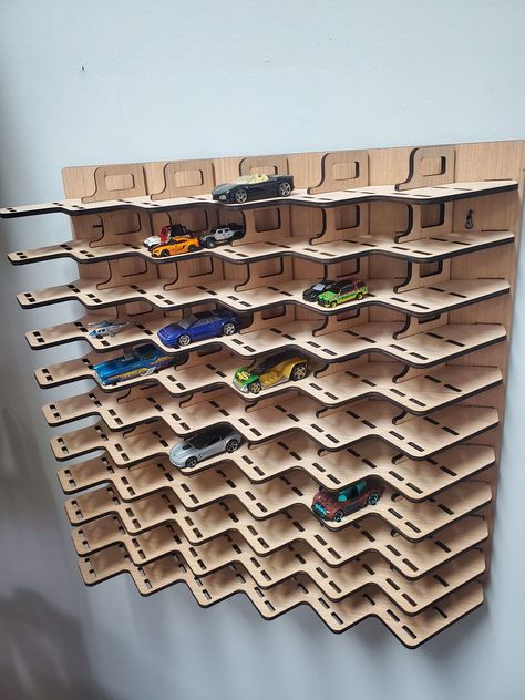 "This combination design holds up to 66 1:64 scale cars OR up to 264 of the micro/nano cars. This is the original Artifact Design diagonal display design (unlike the copies made in China) cut from 3/16 plywood. We use sustainably sourced domestic wood and make at our home here in the USA!   1 Laser cut 3/16 plywood matchbox car display rack.  Entire rack measures only 17\" by 17\".  Rack will hold 66 1:64 matchbox die-cast cars. Slots are slightly oversized at 3.5\"x1.5\" to hold the longer and Artifact Design, Matchbox Car Storage, Hot Wheels Cars Display, Matchbox Cars Display, Laser Cut Wood Ornaments, Toy Car Display, Hot Wheels Wall, Laser Cut Wood Jewelry, Car Room Decor