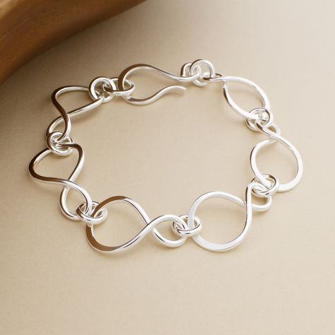 Forged by hand in solid sterling silver, the Infinity Link Bracelet features asymmetrical figure-eight links that are artfully hammered along the curve. The bracelet is completed with our signature hook clasp. This bracelet is made-to-order by hand in our bespoke metalsmithing studio in Stockport, New York. Instead of casting multiples of our designs, we fabricate each element by hand the old-school way using torches, hammers, and files on raw silver. Therefore, each bracelet is truly handmade a Adjustable Hand Forged Sterling Silver Bracelet, Handmade Silver Bangle, Silver Link Bracelets With Hook And Links, Handmade Silver Chain Link Bracelet, Hand Forged Silver Swirl Jewelry, Silver Smithing Jewelry, Organic Silver Jewellery, Artisan Hand-strung Sterling Silver Bracelets, Silversmithing Jewelry