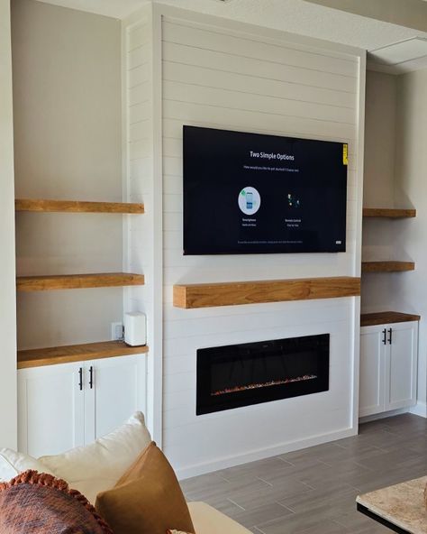 Elevate your living space with our custom entertainment center designs! 🎨✨ This latest project showcases a beautiful blend of modern aesthetics and functional design, featuring built-in shelving, a sleek electric fireplace, and a perfectly mounted TV. The natural wood accents add warmth and contrast beautifully against the shiplap backdrop, creating a cozy and inviting focal point in this home. Whether you’re looking to upgrade your living room or create a stunning feature wall, we’ve got yo... Shiplap With Built Ins, Railing Between Kitchen And Family Room, Electric Fireplace Wall With Built Ins, Modern Living Room With Electric Fireplace, Diy Fireplace Entertainment Center, Diy Built In Entertainment Center With Electric Fireplace, Diy Tv Built In, Build Fireplace Wall, Shiplap Fireplace Wall With Tv