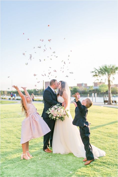 Armature Works Rooftop 220 Wedding | Tiffany McClure Photography | Spring Wedding in Tampa | Blush cream and greenery wedding color palette | Rooftop Wedding Ceremony | Rustic Exposed Brick Reception Venue | Blush Spring Florida Wedding | Blended family wedding photo | Adorable Wedding Photo with Step Children | Wedding photo tossing flower petals Wedding Pics With Kids, Family Wedding Photos With Children, Wedding Photography With Children, Wedding Photo Ideas Flowergirl, Bride And Groom Kissing At End Of Aisle, Rooftop Wedding Ceremony, Blended Family Wedding, Wedding Photo Walls, Photo Booth Backdrop Wedding