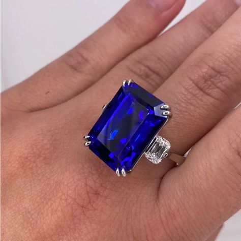 Did you know– tanzanite was introduced by Tiffany & Co. in 1968 and is celebrated for its stunning blue-violet hue. This exquisite custom, artisan-made platinum ring features a 19.97-carat emerald-cut tanzanite and is accentuated by two antique cushion-cut diamonds totaling 1.02 carats, along with 36 round diamonds adding up to 0.14 carats. The beautiful blue of this ring is reminiscent of the ocean and perfect for summer! Brilliant Cut Tanzanite Diamond Ring, Luxury Tanzanite Diamond Ring Round Cut, Blue Brilliant Cut Tanzanite Ring, Brilliant Cut Round Tanzanite Gemstones, Silver Tanzanite Gemstones With Brilliant Cut, Antique Cushion Cut Diamond, Antique Cushion Cut, Antique Cushion, Tanzanite Diamond Ring