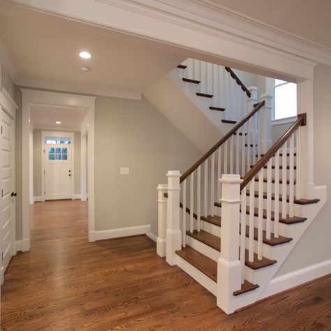 The beautiful U-shaped stair has hardwood treads and handrails with painted white risers, newel post and pickets. White Stair Risers, U Shaped Stairs, Banister Remodel, U Shaped Staircase, Stairs Trim, Entryway Stairs, Open Stairs, Stair Makeover, Traditional Staircase