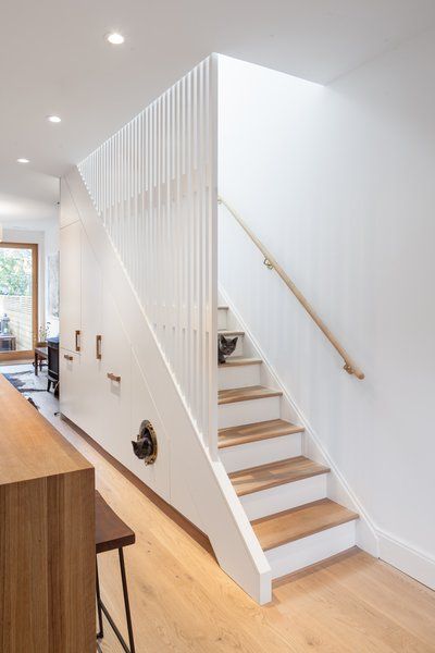 Kitchen, Refrigerator, Wood Counter, Marble Counter, White Cabinet, and Light Hardwood Floor CAB Architects deftly hid appliances, pantry storage, and a litter box for the owners' two cats in the cabinetry beneath this staircase. Edwardian House Renovation, Staircase Wood, Modern Staircases, House Renovation Projects, Staircase Storage, Wood Railing, Stairs Design Modern, Edwardian House, Home Stairs Design