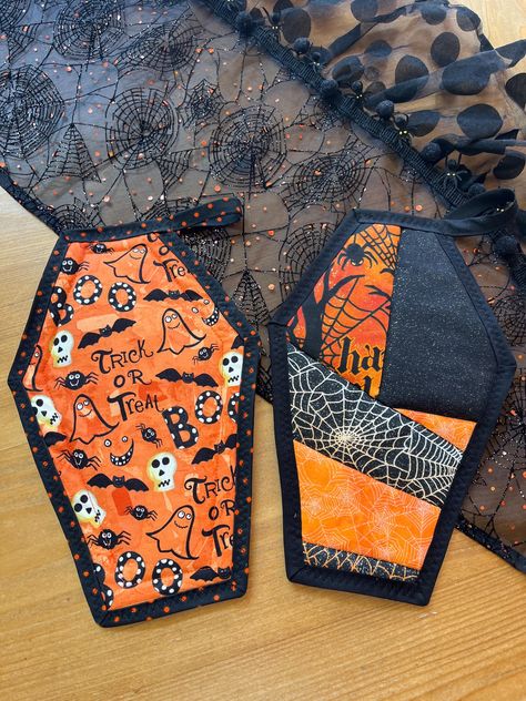 Handmade Halloween coffin quilted pot holder/hotpad. There are two variations, the first one is a patchwork design with black trim and the second one has black with orange polka dot trim and "Spooky Night" embellishment. Both are reversible and have had tabs. Insulated with ironing board fabric and batting for heat protection. Includes hang tab. Size is 11.0 " wide X 7.0" high This item is handmade. Halloween Sewing Crafts, Halloween Quilt Patterns, Crazy Quilts Patterns, Halloween Sewing, Spooky Night, Halloween Coffin, Mug Rug Patterns, Holiday Sewing, Quilt Rack