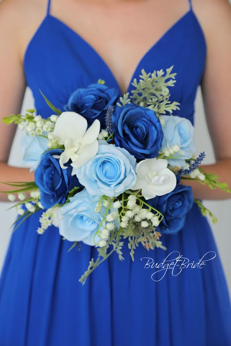 This brides’ bouquet is the perfect option if you have chosen horizon or capri blue as one of the accent colors for your wedding. A lovely array of horizon and capri blue roses with pops of blue lavender sprigs are center-stage in this stunning arrangement. Stunning white hydrangea, lily of the valley, orchids, and stephanotis add beautiful contrast alongside the blue roses. Lush foliage in dusty green polish off this romantic and beautiful design. As always, this bouquet has been wired by hand Royal Blue Bridesmaid Bouquet, Royal Blue Prom Bouquet Ideas, Royal Blue And Green Wedding Theme, Royal Blue Bouquet Prom, Royal Blue Prom Flowers Bouquets, Wedding Flower Arrangements Blue, Royal Blue And White Wedding Theme, Royal Blue Flower Bouquet, Bride Bouquets Blue