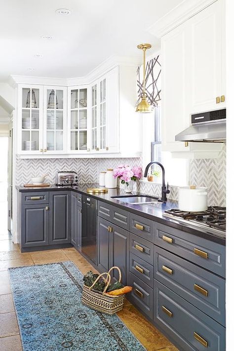 Amazing kitchen features white upper cabinets and gray lower cabinets adorned with brass hardware paired with black quartz countertops and white and gray marble chevron backsplash tiles. White Upper Cabinets, Серая Кухня, Country Kitchen Designs, Gray Cabinets, New Kitchen Cabinets, Classic Kitchen, Kitchen Decorating, Kitchen Redo, Trendy Kitchen