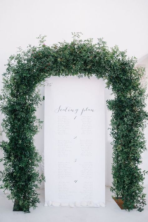 Rustic greenery arch wedding escort seating char Greenery Arch, Arch Wedding, Modern Minimalist Wedding, Event Signage, Santorini Wedding, Wedding Ceremony Flowers, Greenery Garland, Greece Wedding, Ceremony Flowers