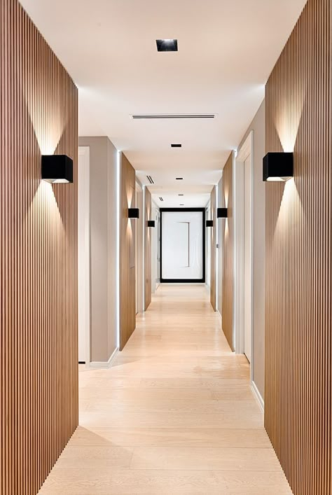 Black rectangle simple minimalistic wall sconces with up and down lighting in this infinity hallway. Using custom wood panels and lighting to create a hotel-like atmosphere. Contemporary Hallway, Decoration Hall, Dentist Office Design, Dental Office Design Interiors, Hotel Corridor, Hotel Hallway, Medical Office Design, Corridor Design, Lift Lobby