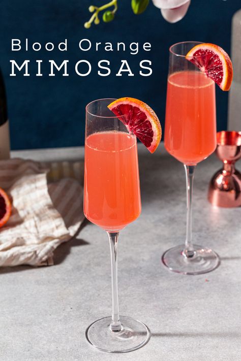 Two blood orange mimosas on a countertop, garnished with fresh blood orange slices and with some ingredients and bar tools in the background. Text overlay at the top says "blood orange mimosas". Blood Orange Mimosa, Orange Champagne Cocktail, Blood Orange Aesthetic, Bridal Shower 2023, Non Alcoholic Champagne, Orange Mimosa, Shower 2023, Blood Orange Margarita, Halloween Drink