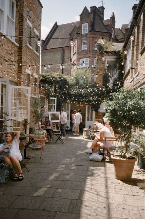 A bright summer day on a small street off Columbia Road Market in East London. The street has cafes with outdoor seating, and strings of fairy lights hanging between the buildings. Lucy Moon, Professional Overthinker, Columbia Road Flower Market, Columbia Road, London Lifestyle, The Good Witch, Travel Reading, Rustic Theme, London Street