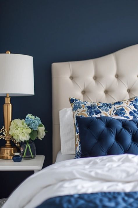 A beautifully decorated bedroom showcasing navy blue walls, layered with gold accents in beddings and decor, illustrating elegant design inspiration. Blue Gold Room Aesthetic, Blue And Gold Master Bedrooms Decor, Gold And Navy Bedroom Ideas, Navy White And Gold Bedroom, Gold Room Aesthetic, Blue Gold Room, Navy Blue And Gold Bedroom, Navy And Gold Bedroom, Blue And Gold Bedroom Ideas