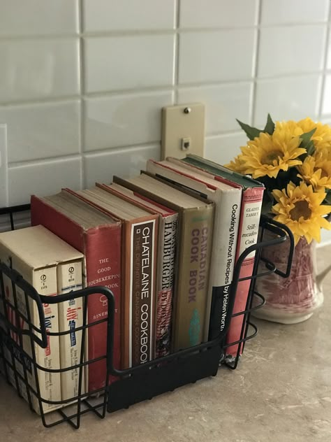 How to display vintage cookbooks on counter top Cookbook Display In Kitchen Counter, Cook Books In Kitchen Ideas, Countertop Cookbook Storage, Silverware On Countertop, Kitchen Cook Book Storage, Old Cookbooks Display, Cookbooks On Counter, Cookbooks On Top Of Fridge, Cook Book Display On Counter