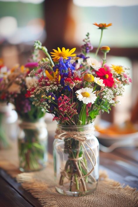 Discover the perfect blend of simplicity and elegance for your big day! 🌼💐 Our DIY wedding centerpieces feature vintage mason jars, handpicked wildflowers, and natural twine accents. Create a cozy, romantic atmosphere at your reception. #WeddingInspiration #RusticWedding #DIYBride #MasonJarDecor #WildflowerCenterpieces #VintageWeddings #SimpleElegance #RomanticDecor Wildflower Table Arrangements Wedding, Rustic Spring Wedding Centerpieces, Wedding Table Wildflowers, Wildflower Farm Wedding, Cute Wedding Themes Ideas, June Garden Wedding, Summer Wedding Wildflowers, Wildflower Backyard Wedding, Wildflower Arrangements Simple