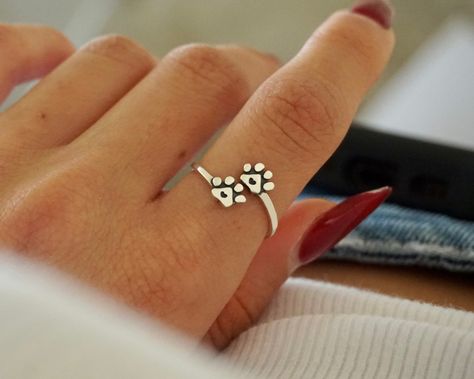 An adorable yet classic paw print ring that symbolizes unconditional love for your dog, cat, and/or loyal companion. It is a lovely way to symbolize how much you love your pet. Celebrate the everlasting bond you share by treating yourself with this paws-itively perfect piece. Ideal for the obsessed animal lover, this paw print ring with heart symbol is the perfect gift for a loved one or a beautiful piece of art that compliments your unique and individual style. It may be worn alone or in combination with other rings! 100% Handmade in Boca Raton, FL Each ring is made to order.  Available in Sterling Silver, Yellow Gold, and Rose Gold.  -Adjustable  Perfect gift for any occasion and any age. Made from pure high-quality 925 Sterling Silver. Hypoallergenic, nickel-free cast material. Will not Solid Gold Womens Ring Paw Print, Adjustable Paw Print Jewelry For Gift, Sterling Silver Jewelry With Paw Print, Paw Ring, Paw Print Ring, Dog Lover Jewelry, Paw Jewelry, Paw Heart, Memorial Ring