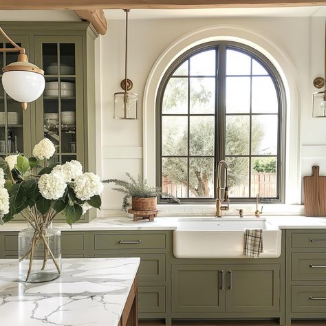 Olive green is one of the trending colors of the year! These cabinets play on trend while remaining a timeless contrast, and I love the warmth they add to this space. With a modern color, these rustic beams, farmhouse sink, and English cottage finishes help create a beautiful balance! AI Design: @oakhavendesignco . . . . . . . . . . #virtualdesign #virtualdesignservices #edesign #virtualhomedesign #moodboards #luxeathome #visionboards #prettylittleinteriors #interiorstyle #smmakelifebeauti... Arch Window Kitchen Sink, Arch Over Kitchen Sink, Arch Window In Kitchen, Arched Window Kitchen, Arched Kitchen Window, Arch Over Stove, Warm Farmhouse Kitchen, Olive Green Interior Design, Modern English Cottage Interiors