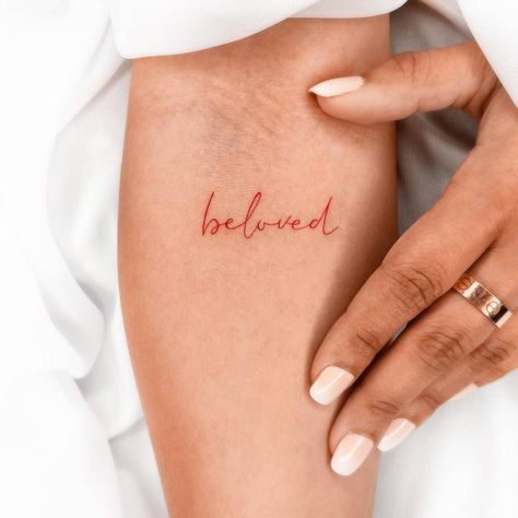 Tattoo of the word "beloved" in red ink located on the Red Wording Tattoo, Red Written Tattoo, Red Writing Tattoo, Red Lettering Tattoo, Red Script Tattoo, Bold Red Word Tattoo, Beloved Tattoo Font, Beloved Tattoo, Red Tattoos