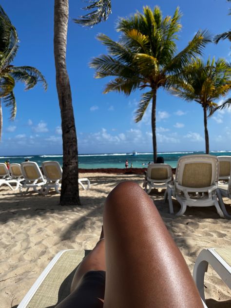 Sun tanned legs on a beach in Riu Ocho Rios, Jamaica with blue ocean waves and palm trees in the background. Beach In Jamaica, Ocho Rios Jamaica Aesthetic, Summer In Jamaica, Ocho Rios Jamaica Pictures, Ochos Rios Jamaica, Jamaica Beach Aesthetic, Jamaica Vacation Aesthetic, Jamaica Pics, Riu Ocho Rios Jamaica