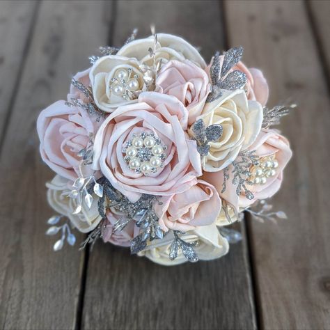 At Rose & Bee we love our Brooch Bouquets!! Created with wood flower roses in light pink and natural cream and filled with silver brooches and silver filler. Our wood flowers never die so plan early and start checking off the boxes on your wedding planning checklist! #bridalbouquet #broochbouquet #weddingplanning #woodflowers #woodflowerbouquet #woodenflowers Quince Bouquet, Wedding Flower Alternatives, Wooden Flower Bouquet, Quinceanera Bouquet, Wood Roses, Mum Ideas, God Mother, Wood Flower Bouquet, Bouquet Rose