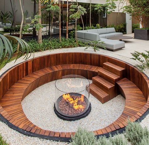 a contemporary sunken fire pit with a built in stained bench and steps plus a fire pit in the center clad with glass Sunken Patio, Sunken Fire Pits, Outdoor Fire Pit Designs, Fire Pit Landscaping, Fire Pit Area, Fire Pit Designs, Backyard Fire, Backyard Garden Design, Fire Pit Backyard