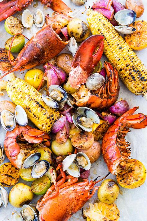 New England Clambake made with clams, lobster, Old Bay, sweet corn, and potatoes, is a summer classic. Easy to make at home. Clambake Recipe, Pescetarian Recipes, Boiled Food, Clam Bake, Lobster Recipes, Beach Meals, Seafood Boil, Food Words, Sea Food