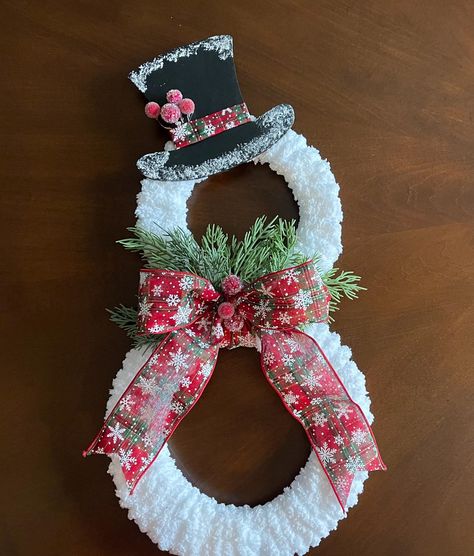 This charming handmade snowman wreath is the perfect addition to your holiday decor! Crafted with soft, fluffy yarn, this wreath mimics the look of freshly fallen snow. The snowman design features a whimsical top hat adorned with frosty detailing and cheerful snowy accents, along with a festive red and green bow decorated with snowflakes. Sprigs of greenery add a natural, wintry touch, completing the snowman's look. Measuring approximately 19 inches tall, this delightful snowman wreath will make a wonderful statement on your front door or as part of your indoor holiday decor. Ideal for welcoming guests, this wreath is a great gift idea or a perfect addition to your own Christmas collection. Display it on your door, between doors, or on a wall to spread holiday cheer all season long. **Prod Wreaths Winter, Snow Man Hat, Snowman Wreaths For Front Door, Snowman Wreath Ideas, White Christmas Wreaths For Front Door, Snowman Wreath Form, Mesh Christmas Wreath, Embroidery Hoops Ideas, Snowman Decorating Ideas