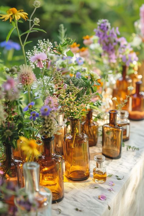 Elevate your wedding decor with a unique touch of the past. These vintage perfume bottles turned vases are filled with an array of herbs and wildflowers, perfect for a bohemian-themed celebration. 🌿🌼💐 A touch of nostalgia meets natural beauty for your special day. #WeddingInspiration #BohoWedding #CenterpieceIdeas #VintageDecor #FloralDesign #DIYWedding #EventStyling #WeddingFlowers Vintage Vases Wedding Centerpieces, Outdoor Wedding Floral Decorations, Vintage Table Decorations Wedding, Bohemian Chic Wedding Decor, Wild Flower Centerpieces Wedding Simple, Wedding Decor Wildflowers, Dried Flower Table Decor, Wildflower Vintage Wedding, Table Decor Wedding Rustic