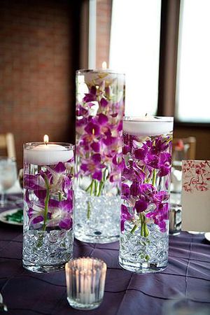 Flowers submerged in a case filled with water and topped with floating candles wedding centerpiece ideas Purple Floating Candles, Floating Flower Candles, Spring Wedding Centerpieces, Floating Candles Wedding, Purple Table, Candles Wedding, Tafel Decor, Candle Wedding Centerpieces, Wedding Table Decorations