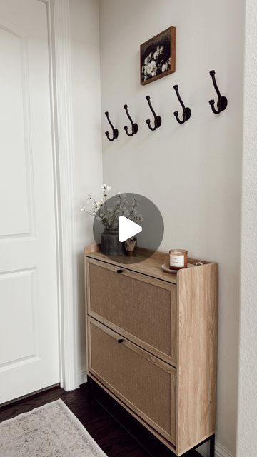 Nina Humes on Instagram: "small entryway 🤍✨

that is budget friendly and functional! This is the entry we have by our garage and my husband’s home office. We used to have a console here where I stored our shoes but when I stumbled on this cabinet that concealed everything I knew it would be absolutely perfect here! I LOVE it!

details here:
+ shoe storage cabinet: very affordable and under $80 🤯
+ black planter: Walmart
+ faux florals: these are from Hobby Lobby but found near identical ones on amazon
+ candle I love
+ little candle tray that is an older Target find
+ artwork from Amazon
+ washable runner
+ hooks: Amazon find (still deciding if I want to keep these here. I can still hang shorter sweaters and jackets but because this cabinet is taller than my last, I might remove them. We Small Entryways Shoe Storage, Small Hallway Storage Ideas, Small Entryway Shoe Storage Ideas, Small Entryway Storage, Small Apartment Entryway, Little Candle, Apartment Entryway, Amazon Shoes, Black Planters